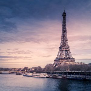 Beautiful wide shot of Eiffel Tower in Paris surrounded by water with ships under the colorful sky A beautiful wide shot of Eiffel Tower in Paris surrounded by water with ships under the colorful sky
